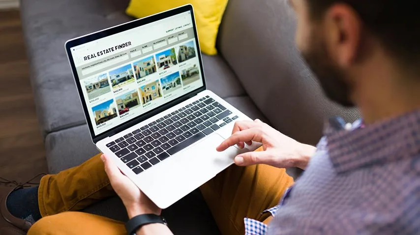 Person browsing property listings on a real estate website on a laptop