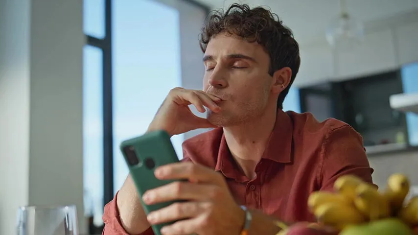 Frustrated man checking his phone after months without construction updates from his broker